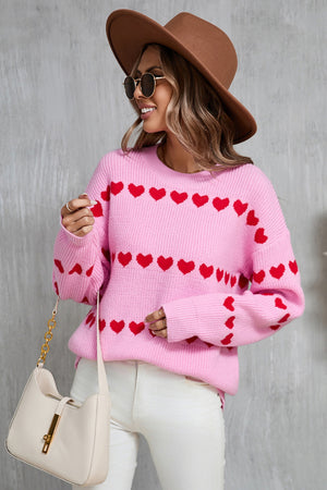 Pink knit pullover sweater with red heart stripes, crew neck, long sleeves.