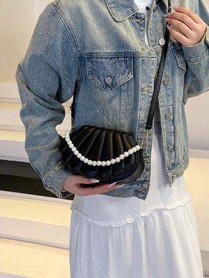 Black shell crossbody bag with pearl embellishment and crossbody strap.
