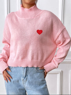 Blush pink cropped turtleneck knit sweater with embroidered red heart detail.