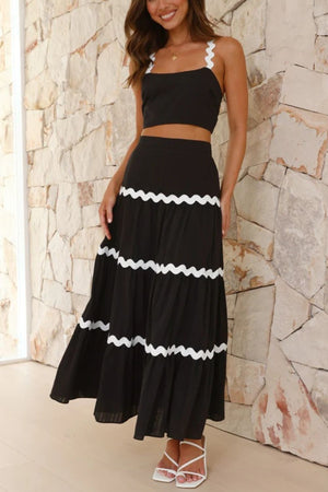 Black crop top with scalloped straps and tiered maxi skirt with white scalloped trim.