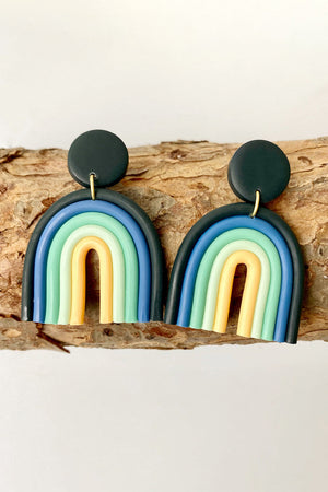 Rainbow arch clay earrings in Dusty Blue, Aqua, and Yellow with dark green studs.