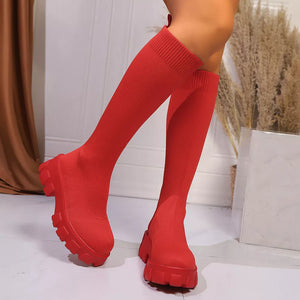 Red knee-high sock boots with chunky platform soles and ribbed cuffs.