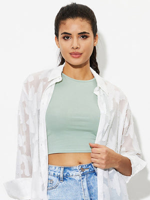 Sage high-neck crop tank top with a casual fit, worn with jeans and an open white shirt.