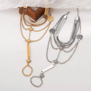 Chic multi-layered chain bracelet in gold and silver with coin details and a ring attachment.