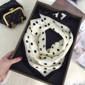 Cream white silk scarf with black polka dots and a bordered edge.