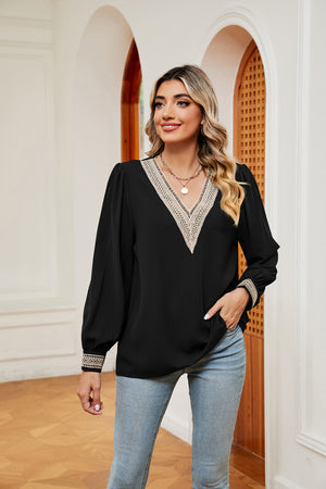 Black blouson top with V-neck and embroidered trim on neckline and cuffs.