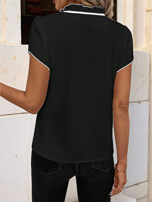 Black maternity blouse with white trim on ruffled tie-neck and short sleeves.