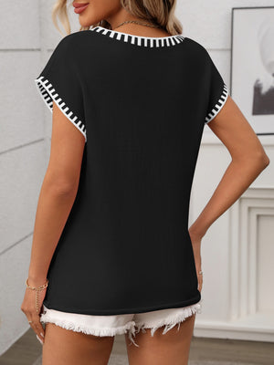 Black knit V-neck top with white contrast trim on neckline and sleeves.