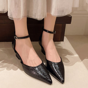 Black pointed-toe ankle strap heels with adjustable buckle and textured finish.