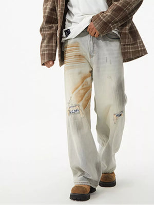 Distressed wide-leg jeans in light wash denim with unique patches and paint details.