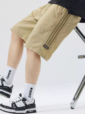 Khaki casual drawstring shorts with sporty side stripes and a number patch.