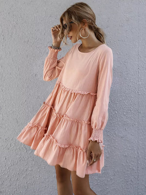 Apricot ruffled mini dress with long sleeves and smocked cuffs, tiered skirt.