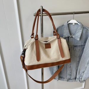 Canvas weekend holdall duffel bag with brown leather trim and straps, and a detachable shoulder strap.