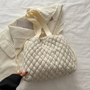 Ivory quilted drawstring carryall bag with textured pattern and dual straps.