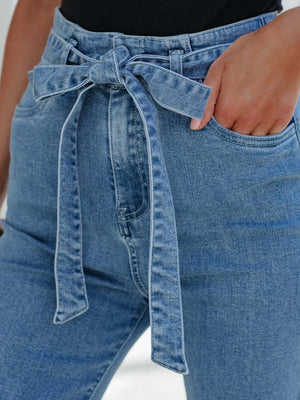 Belted high-waisted flare jeans in light wash denim with a tie waist detail.