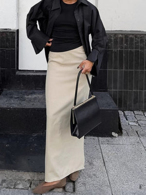 Chic cotton midi skirt in beige with a subtle slit, styled with a black top and shirt.