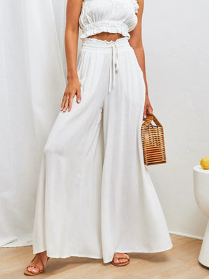 White gathered waist wide-leg palazzo pants with drawstring detail and flowy silhouette.