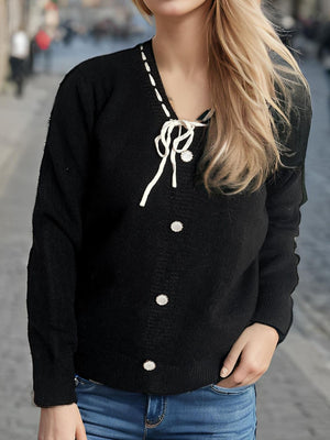 Black knit cardigan with ribbon tie, white contrast stitching and pearl buttons.
