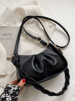 Black ruched crossbody bag with braided strap detail and gold buckle.