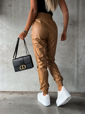 Brown leatherette gathered waist joggers with elastic cuffs and a black handbag.