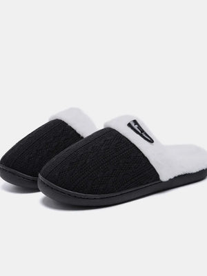 Black cable knit shearling house slippers with white trim and a black accent detail.