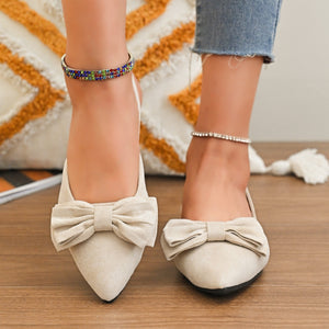 Beige slingback flats with bow detail, pointed toe, and ankle strap.