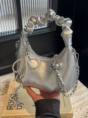 Silver ruched mini crossbody bag with pearl and heart pendant details and chain strap.
