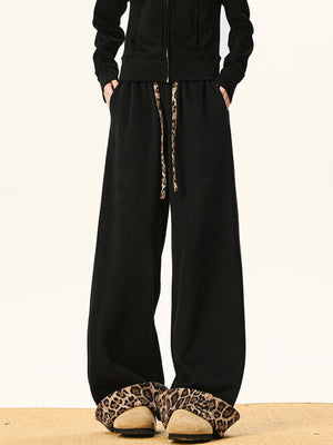 Black sweatpants with wide legs and leopard print drawstring.