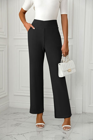 Black wide-leg trousers with a sculpted waist and pockets, styled with a white top and handbag.