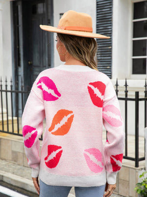 Pink V-neck knit pullover sweater with all-over red, pink, and orange kiss print.