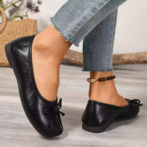 Black Tabi slip-on flats with bow detail and split toe, worn with jeans.