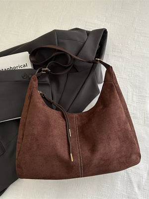 Brown suede crossbody bag with adjustable strap and drawstring detail.