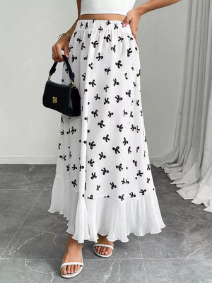 White maxi skirt with black bow print and pleated ruffle hem.