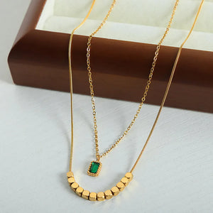 Gold layered necklace with emerald cube pendant and gold bead accents