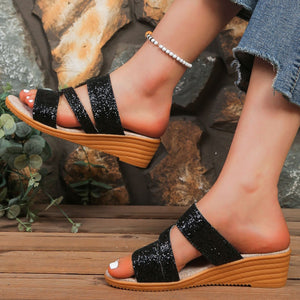 Black sequined wedge sandals with crisscross straps and a wooden wedge heel.