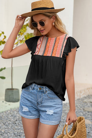 Black blouse with embroidered yoke and ruffle sleeves, paired with denim shorts.