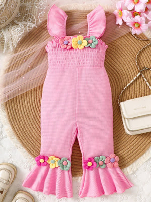 Pink cotton smocked jumpsuit with floral applique on bodice and flared legs.