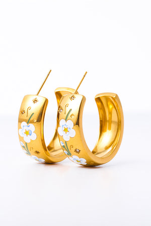 Gold hoop earrings with white floral enamel and delicate star details.