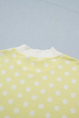 Pastel yellow polka dot polyester top with white ribbed neckline.