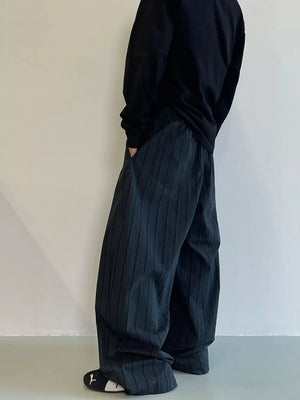 Men's dark grey wide-leg sweatpants with vertical texture and pockets.