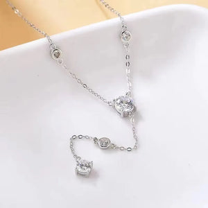 Silver lariat necklace with moissanite drop details and bezel-set stones.