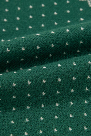 Dark green knit sweater with a white snowflake Fair Isle pattern.