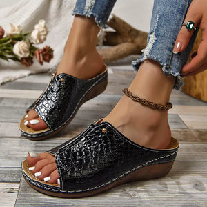 Black glossy crocodile-embossed wedge sandals with open toe and comfortable slip-on style.