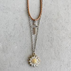 Layered necklace set with silver cross and gold sunflower charm with clear crystals.