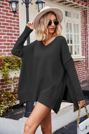 Black acrylic knit sweater with v-neck, asymmetric hemline, and ribbed sleeves.