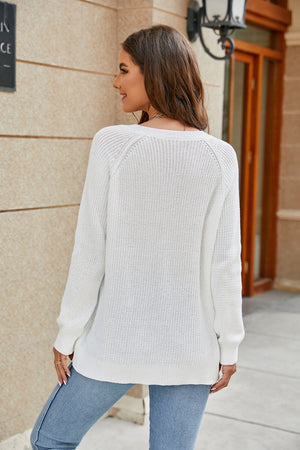 White relaxed V-neck raglan knit sweater with ribbed cuffs and hem.