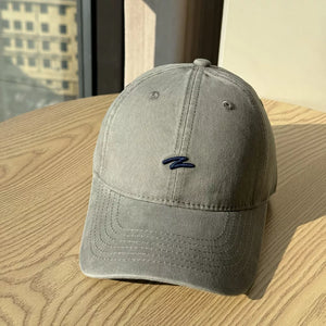 Distressed vintage cotton baseball hat in dark gray with embroidered detail and curved brim.