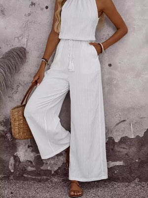 White crinkled wide-leg jumpsuit with tassel drawstring and halter neck.