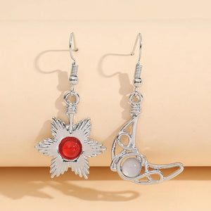 Silver asymmetrical drop earrings with a sun and moon design, featuring a red gem and a white gem.