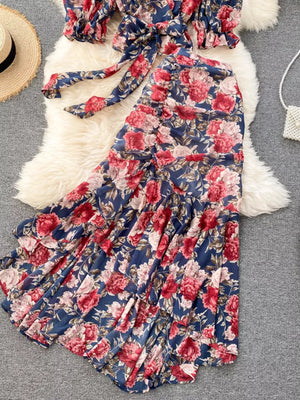 Chic floral two-piece crop set in dark blue with red and pink flowers, featuring a tie-front top and tiered ruffled skirt.
